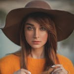 Elegant portrait of a woman in a hat and sweater outdoors in Paris.